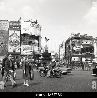 1960, historische Abbildung, die den berühmten Adverising Anschlagtafeln am Kreisverkehr an einer belebten Piccadilly Circus, London, England, mit Motor Verkehr um die shaftsbury Memorial Fountain - häufig, aber fälschlicherweise als Eros bekannt - in der Mitte der Kreuzung. Stockfoto