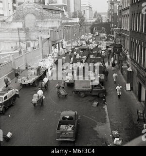 1960, historische Bild Torhüter angezeigt mit Schubkarren in einer Straße, die neben der Obst- und Gemüsemarkt am Covent Garden in London, England. Dieses berühmten Markt setzte sich bis in die späten 60er Jahre, bis die Verkehrsbelastung der Lkw verursacht wurde, bedeutete, dass eine moderne Großhandelsmarkt in den engen Gassen nicht mehr möglich war. Stockfoto