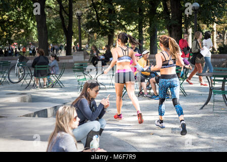 New York City, USA - Oktober 28, 2017: Midtown Manhattan mit Menschen zwei junge Mädchen Frauen laufen, joggen, Sport treiben, im Central Park von Stühlen, ta Stockfoto