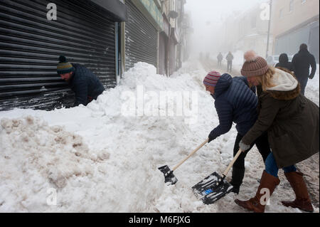 Brynmawr, Blaenau Gwent, South Wales, UK. 3. März, 2018. Ladenbesitzer klar den Schnee vom Geschäft Frontseiten. Viele Autos sind noch mit Schnee bedeckt. Nach den letzten beiden Tagen zerschlagen durch Sturm Emma, Schneefall an, und es ist sehr neblig, aber Winde haben erheblich in Brynmawr, Blaenau Gwent, South Wales, South Wales, UK. (Die höchste Stadt in Wales.) © Graham M. Lawrence/Alamy leben Nachrichten Stockfoto