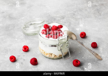 Glanola in Glas Glas mit Himbeeren auf grauem Hintergrund Stockfoto