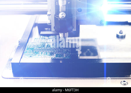 Das Konzept der Technologien der Zukunft. Computer Board mit visuellen Effekten in einem futuristischen Stil. Automatisierung der Zusammenbau der Maschine der Computerplatine. Der Prozess der Löten der Platine. Stockfoto
