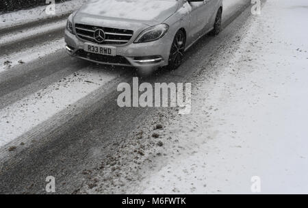 Ein in der Nähe der Räder und Motorhaube von einem silbernen Mercedes Auto im Schnee bedeckte Straße auf der A 36. Stockfoto