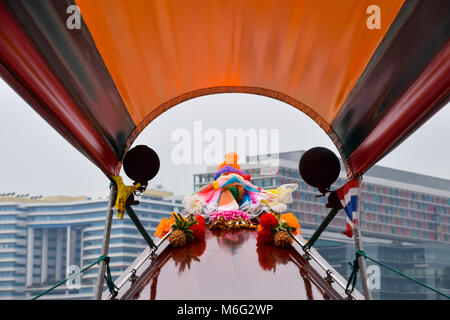 THAILAND, Bangkok - 28. MÄRZ 2016 - der Bug eines traditionellen River Boat Taxi, in Blumen geschmückt werden, zeigen auf modernen Hochhäusern Neben Th Stockfoto