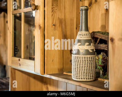 Vintage Keramik bestickt Weinflasche auf Holzregal. Stockfoto