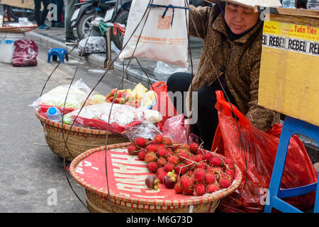 Eine Frau trägt Früchte in Körbe aus ihrem Bambus die Pole in Hanoi, Vietnam umschlungen Stockfoto