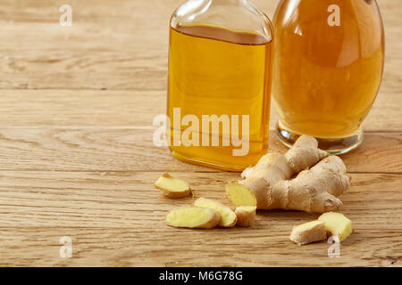 Schönen Komposition eines transparenten Flasche Öl und Glas Öl jar mit Ingwer Wurzel auf rustikalen Holzmöbeln Hintergrund, Nahaufnahme, selektive vocus. Gesundheit Stockfoto