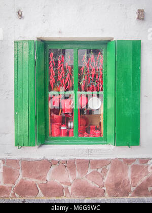 Shuttered alte spanische grüne Fenster mit verschiedenen roten Sachen hinter dem Glas Stockfoto