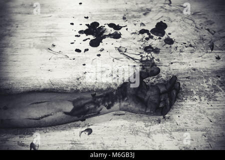 Hand in Blut auf einem weißen Vintage schmutzigen Fußboden in einer Blutlache. Schneiden Sie die Adern auf der Hand eines Selbstmord. Schmutziges Schwarz-Weiß-Foto. Mord mit einem Stockfoto