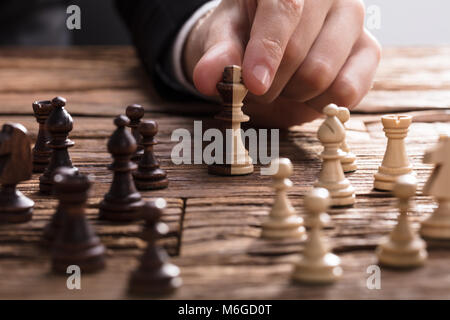 Der Geschäftsmann, der Hand König Schachfigur auf hölzernen Schreibtisch Stockfoto