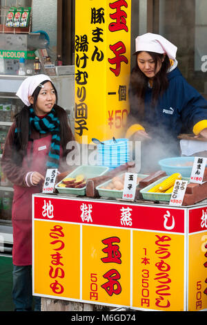 Beppu, Japan. Zwei junge Mädchen, die in den lokalen Markt. Gekochte Eier, Mais und Kartoffeln ist beliebt fast food. Stockfoto