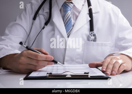 In der Nähe von einem Arzt Hand Analyse Bericht auf weißem Schreibtisch Stockfoto