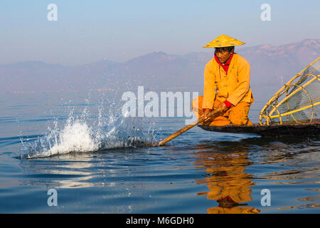 Inle Lake Myanmar Intha Leg Ruderfischer am Inle Lake, Myanmar (Burma), Asien im Februar - Fischer sitzen auf dem Boot plantschen, um Fische anzuziehen Stockfoto