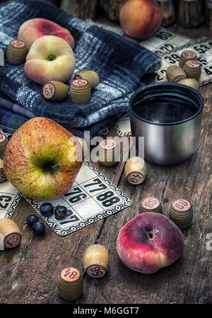 Zubehör Picknick bestehend aus Pfirsiche, Äpfel und Lottospiele. Foto getönt. Stockfoto