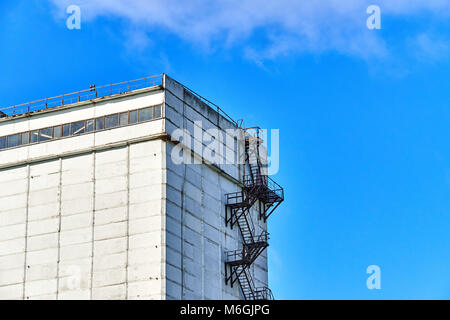 Silogebäude aus Beton mit Feuerleiter auf weißer Fassade vor blauem Himmel Stockfoto