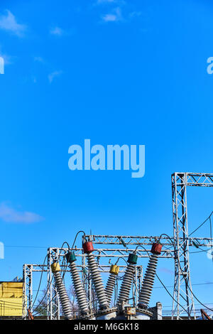 Hochspannungsisolatoren an Transformator-Unterstation gegen blauen Himmel. Energieversorgung der metallurgischen Anlage Stockfoto