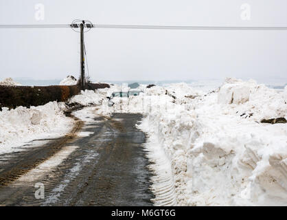 East Lothian, Schottland, Vereinigtes Königreich, 4. März 2018. UK Wetter: Zwei Autos im Schnee begraben auf dem Drem zu Haddington Road nach starker Schneefall infolge der extremen Wetter Veranstaltung, die den Spitznamen "Tier aus dem Osten. Hohen Ufer der Schnee eine schmale Passage Stockfoto