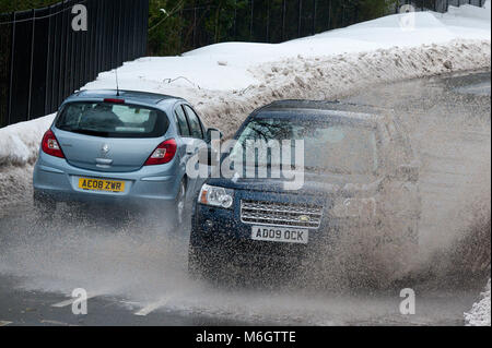 Ebbw Vale, Blaenau Gwent, South Wales, UK. 4. März, 2018. Ein Fahrzeug hits einer großen Pfütze durch schmelzenden Schnee verursacht. Nach dem entsetzlichen Blizzards, die durch Sturm Emma, in South Wales, Temperaturen jetzt gestiegen sind, Schnee zu schmelzen beginnt, und der Niederschlag ist jetzt fallende Regen in Ebbw Vale in Blaenau Gwent. Obwohl viele wichtige Straßen langsam gelöscht werden, Autos sind immer noch in Wohngebieten erfordert ein Fußweg zum Supermarkt für Lebensmittel festgefahrene. © Graham M. Lawrence/Alamy leben Nachrichten Stockfoto