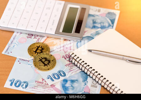 Zwei goldene Bitcoins, Rechner, Journal und Stift auf türkisch Papier Banknoten Stockfoto