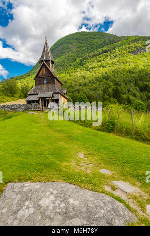 Urnes Stabkirche in der grünen Berglandschaft, Ornes, Norwegen, Weltkulturerbe an der Lustrafjorden, Sognefjorden Stockfoto