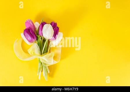 Flach der Bündel von lila Tulpen auf gelben Hintergrund. Kopieren Sie Platz. Stockfoto