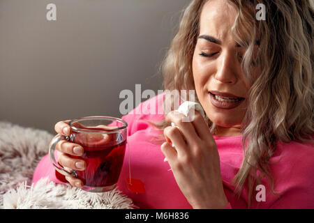 Junge Frau krank im Bett mit Temperatur trinken heißen Tee Stockfoto