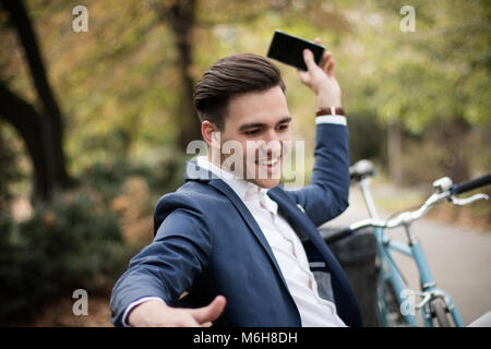 Junge Unternehmer werfen sein Smartphone in den Park. Stockfoto