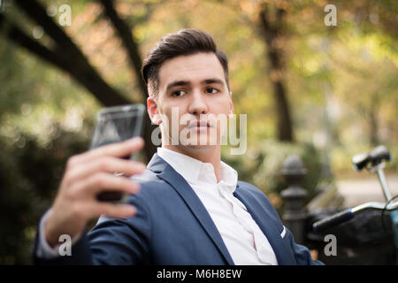 Junge attraktive Geschäftsmann einen selfie mit seinem Smartphone im Freien in einem Park Stockfoto