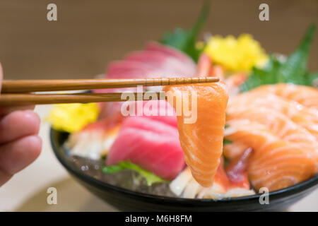 Stäbchen mit Lachs Sashimi mit gemischten geschnittenen Fisch sashimi auf Eis im schwarzen Schüssel. Sashimi Lachs Thunfisch Hamachi Garnelen und Surf Ruhig, roher Fisch, jap Stockfoto