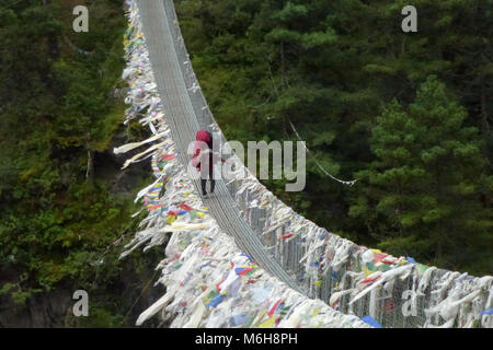 Eine schwere geladen Porter über eine Hängebrücke in Jorsale, Everest Base Camp trek, Nepal Stockfoto