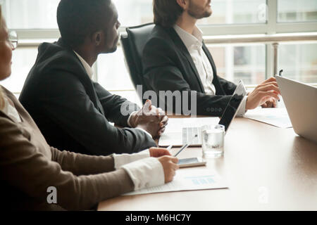 Geschäftsleute, die am Konferenztisch sitzen auf das Hören konzentriert Stockfoto