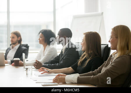 Diverse lächelnd Geschäftsleute sitzen an einem Konferenztisch bei gr Stockfoto