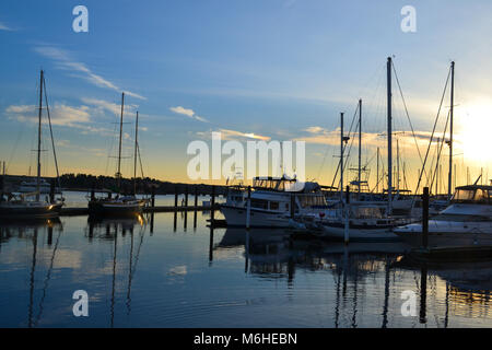 Serenity bei Sonnenuntergang im Hafen. Hohen Masten für Boote schmücken den Himmel, als die Sonne über den Horizont. Ruhiges Wasser, Ruhe, Frieden. Stockfoto