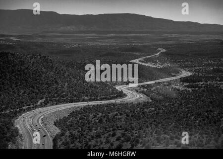 Eine expansive Antenne Landschaft eines Arizona Highway schlängelt sich durch einen großen Wald, aus einem Helikopter. Stockfoto