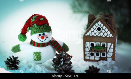 Spielzeug Schneemann und ein Lebkuchenhaus auf einem hellen Hintergrund. Stockfoto