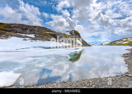 Eis auf einem Bergsee und verschneiten Bergen, Norwegen, Vikafjellsvegen, Riksvei, Rv 13. Stockfoto