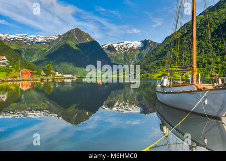 Weißes Segelboot und weißen Berge am Fjord, Bergen in Norwegen, klare Spiegelung im Sognefjorden im herrlichen Morgenlicht. Stockfoto