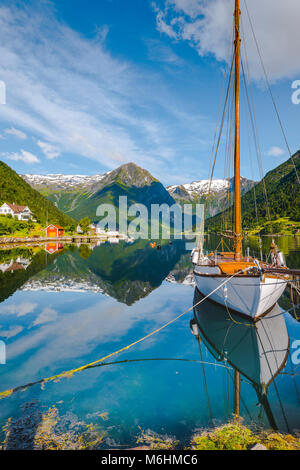 Weißes Segelboot und weißen Berge am Fjord, Bergen in Norwegen, klare Spiegelung im Sognefjorden im herrlichen Morgenlicht. Stockfoto