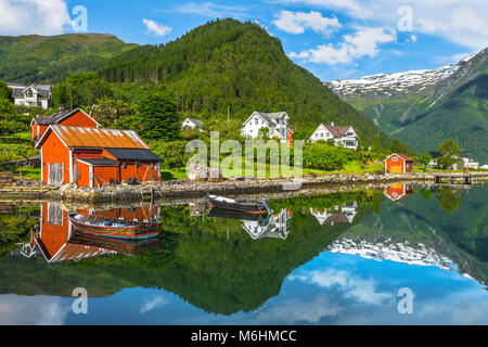 Boote und roten Fischer Hütte, Norwegen, Küste und die Bucht von Balestrand mit Spiegelung der Schnee in den Bergen, Esefjorden, Sognefjorden Stockfoto