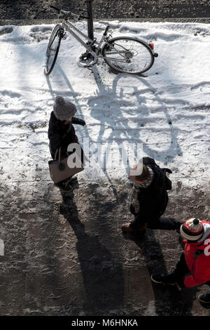 Zu Fuß durch den Schnee in Central London, Blick von oben nach unten mit einem abgestellten Fahrrad, angekettet an einen Laternenpfahl Stockfoto