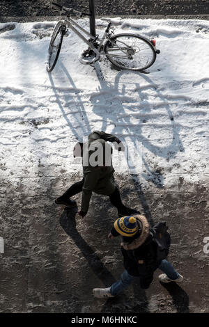 Zu Fuß durch den Schnee in Central London, Blick von oben nach unten mit einem abgestellten Fahrrad, angekettet an einen Laternenpfahl Stockfoto