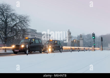 Taxis und Verkehr außerhalb der Buckingham Palace im Schnee Stockfoto