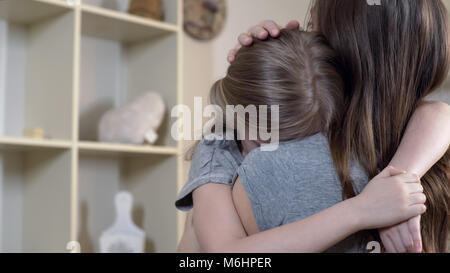 Frau trösteten umgekippt oder kranken Kindes sorgfältig, Mutter umarmt traurige Tochter Stockfoto