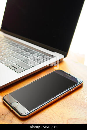Arbeitsplatz mit Laptop und Mobiltelefon auf hölzernen Schreibtisch Stockfoto