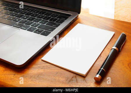 Arbeitsplatz mit einem Laptop, Notizblock und Kugelschreiber auf hölzernen Schreibtisch Stockfoto