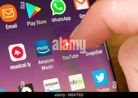 Nahaufnahme der YouTube-App auf einem ausgewählten Smartphone Durch den Finger einer Frau, die auf die App auf dem zeigt Handybildschirm Stockfoto