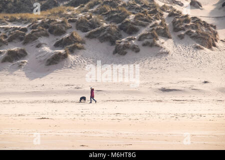 Ein Hund und seinen Besitzer hinter den Dünen mit Blick auf Crantock Beach in Newquay Cornwall. Stockfoto