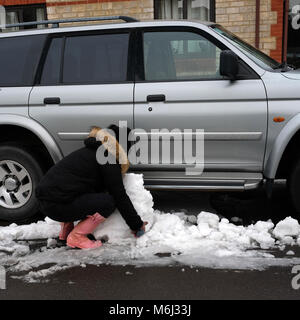 März 2018 - Die gelöschten Schnee rund um Pkw und SUV's geparkt am Straßenrand in der Somerset Village von Cheddar. Stockfoto