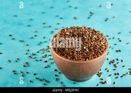 Narural raw Leinsamen in einem keramischen Ton Schüssel auf blauem Hintergrund isoliert, close-up. Nützlich und Ernährung Ölsaaten für das tägliche Kochen. Gesunde eatin Stockfoto