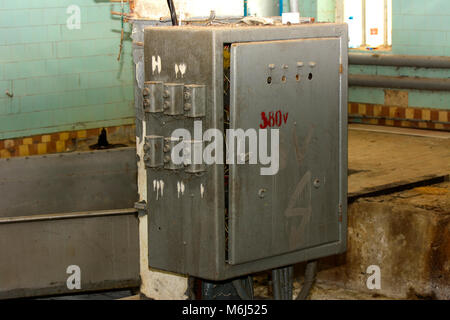 Alte zerlegt und rostige Schalttafel Montage auf einer verlassenen und zerstörten Fabrik vor dem Hintergrund des Chaos. Zerstörung und Vandalismus. Ukrai Stockfoto